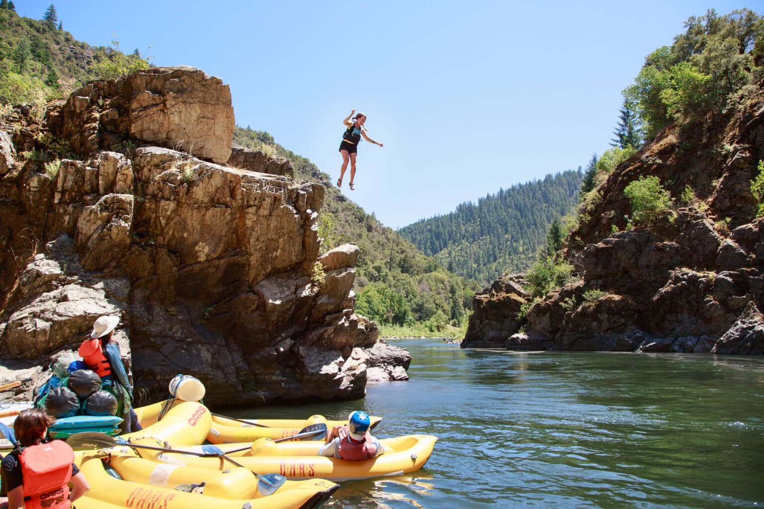 A girl jumps from a cliff into the crystal clear water on Oregon's Rogue River.