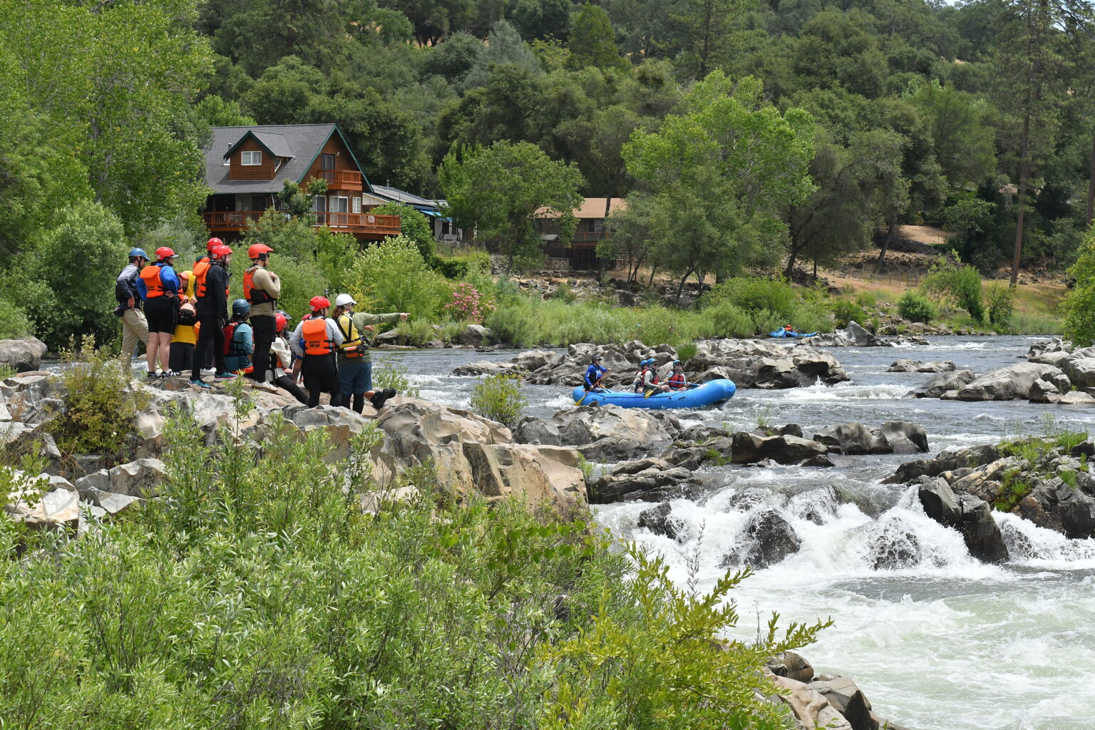 A group of students in an OARS whitewater guide school class scout a rapid on the American River.