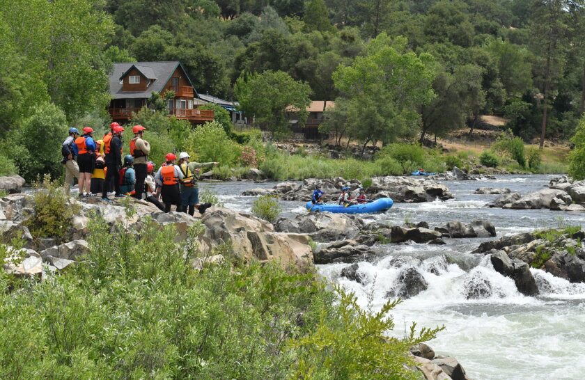 A group of students in an OARS whitewater guide school class scout a rapid on the American River.