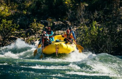 A group of OARS guide school participants rafts through whitewater on the American River.