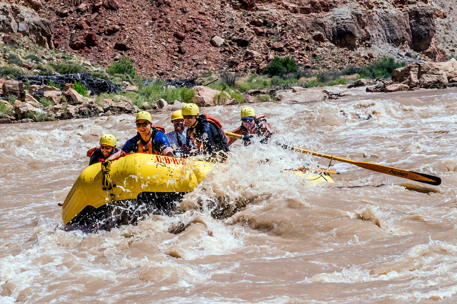 A yellow raft with guests takes on the rapids of Cataract Canyon on the Colorado River