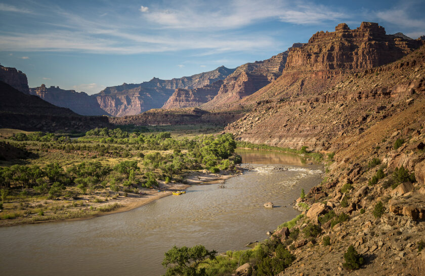 Scenic view of the Green River through Desolation Canyon with yellow rafts at camp in the distance