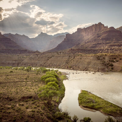 Landscape view of Desolation Canyon on the Green River with sun rays shining through clouds.