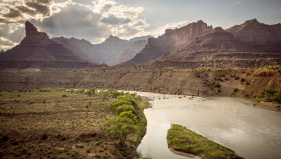 Landscape view of Desolation Canyon on the Green River with sun rays shining through clouds.