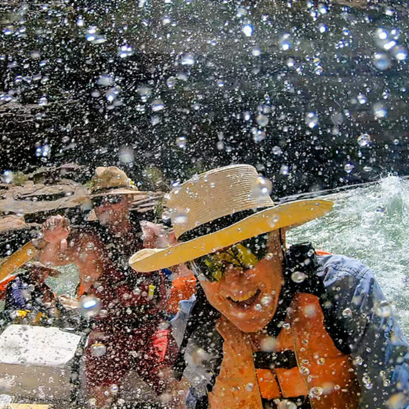 Close up of a guest and guide being splashed by whitewater spray as they go through a rapid on the Colorado River in Grand Canyon