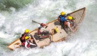 A dory rowed by a guide with four guests crashes through a frothy rapid on the Colorado River in Grand Canyon