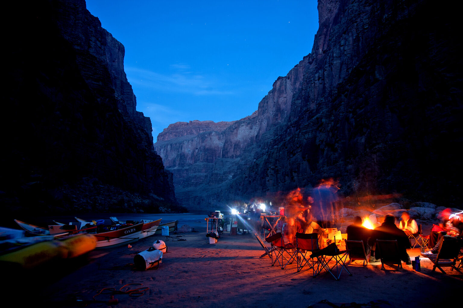 Night time in Grand Canyon on an OARS Dories trip with lights in kitchen and a camp fire