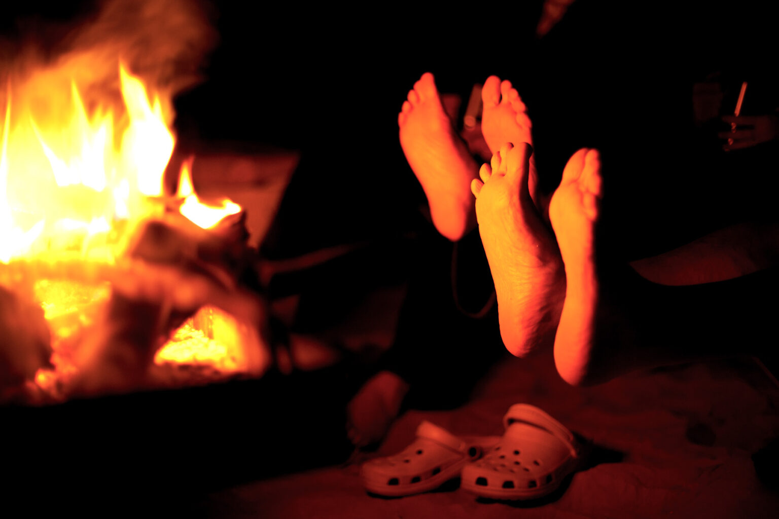 Bare feet warming by an open fire in a late fall Grand Canyon river trip