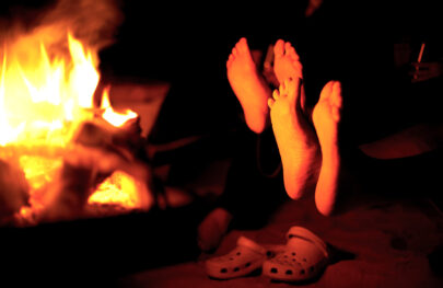 Bare feet warming by an open fire in a late fall Grand Canyon river trip