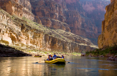 OARS rafts in calm water surrounded by huge cliffs in Grand Canyon