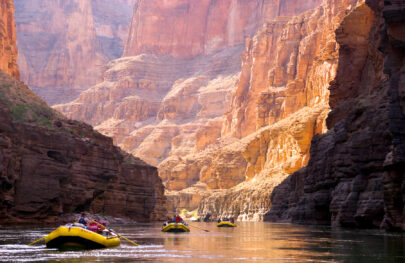 OARS rafts follow in a line through brightly lit canyon at heart of Grand Canyon