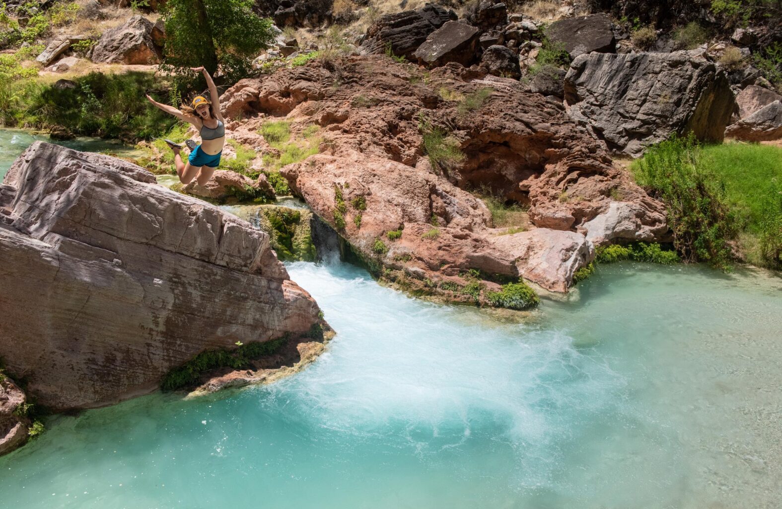 A woman jumps into Havasu Creek on an OARS Grand Canyon trip
