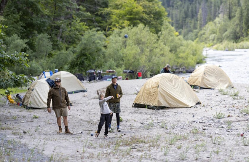 Two adults and a boy play bocci ball on a beach on the Klamath River during a rafting trip with OARS.