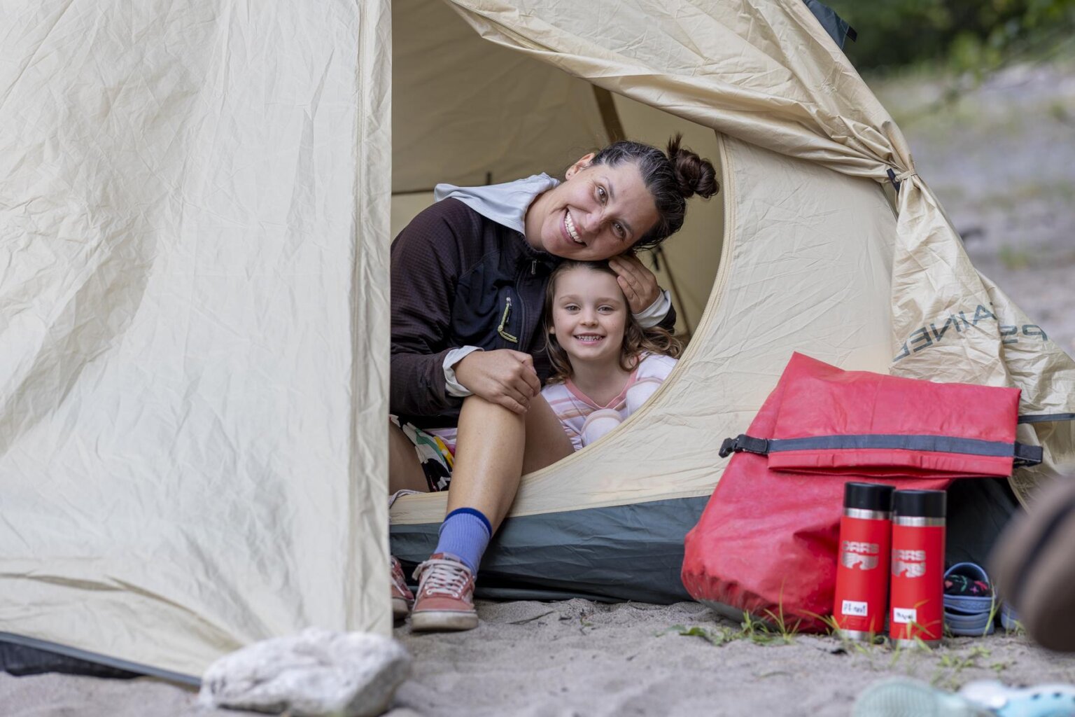 A mother and daughter smile for a photo from their tent during a rafting trip on the Klamath River with OARS.