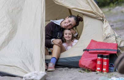 A mother and daughter smile for a photo from their tent during a rafting trip on the Klamath River with OARS.