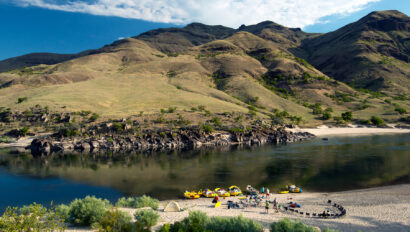 Several OARS boats lined up on a beach at camp on the Lower Salmon River.