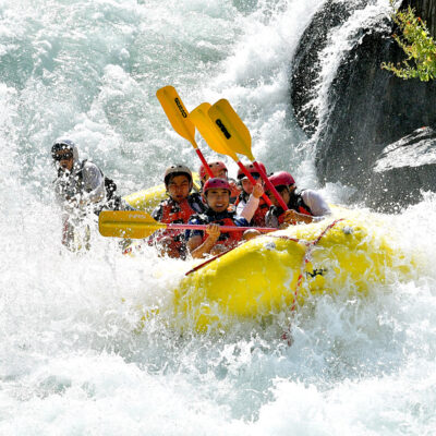 A yellow raft full of paddlers surrounded by frothy whitewater on the Middle Fork of the American River in California
