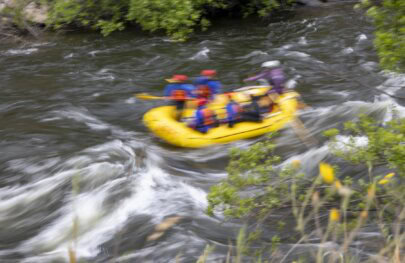 A yellow OARS rafts races by during a rafting trip on the Merced River in May 2025.