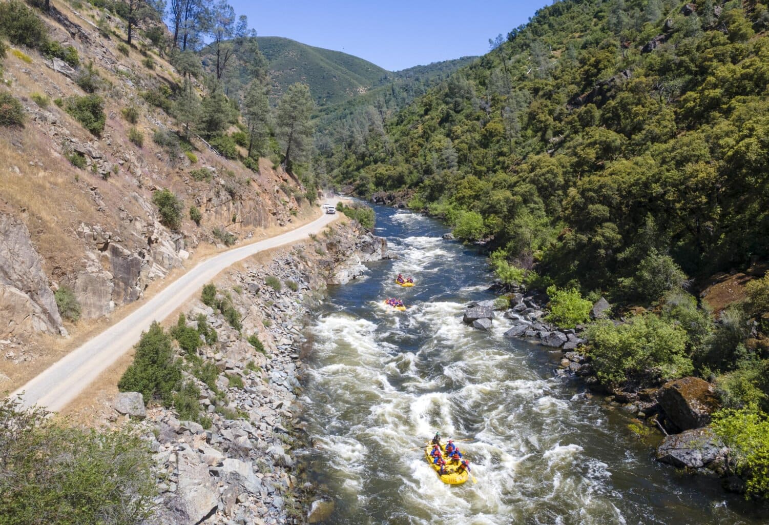 Three yellow OARS rafts float the Merced River near Yosemite National Park.