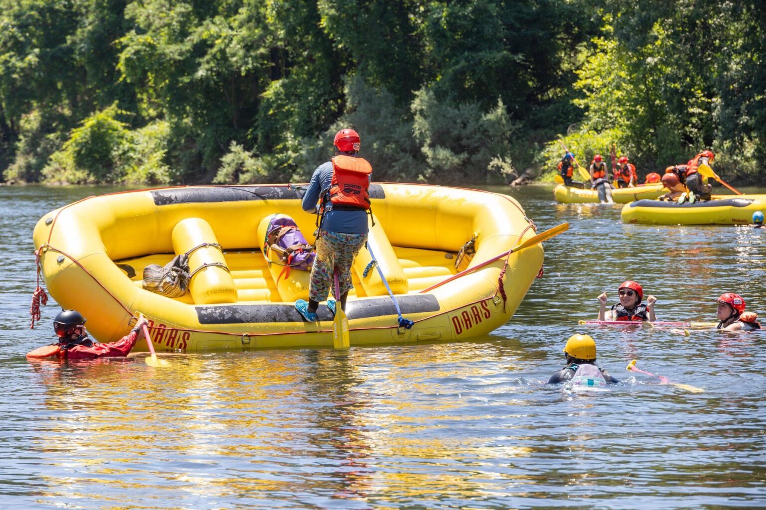 A student in an OARS whitewater guide school practices flipping a raft on the American River.