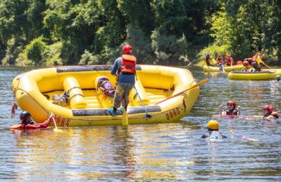 A student in an OARS whitewater guide school practices flipping a raft on the American River.