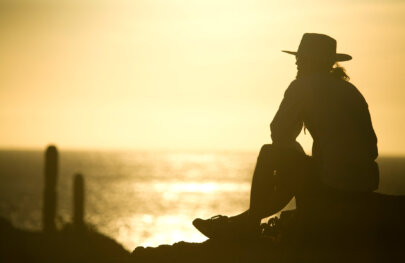 Silhouette of a man sitting on a rock overlooking the ocean as the sun sets in Baja Mexico.