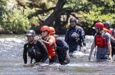 Students in OARS whitewater guide school class practice walking in a river during a swift water rescue training.