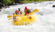 A yellow raft of paddlers surounded by frothy whitewater as they make their way through a rapid on the Tuolumne River in California