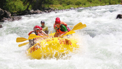 A yellow raft of paddlers surounded by frothy whitewater as they make their way through a rapid on the Tuolumne River in California