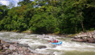 A paddle raft going through rapids surrounded by lush rainforest on a Costa Rica Pura Vida trip