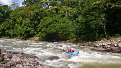 A paddle raft going through rapids surrounded by lush rainforest on a Costa Rica Pura Vida trip