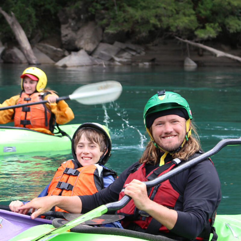 A guide and young guest smile for the camera in their kayaks on the Futaleufu in Chile