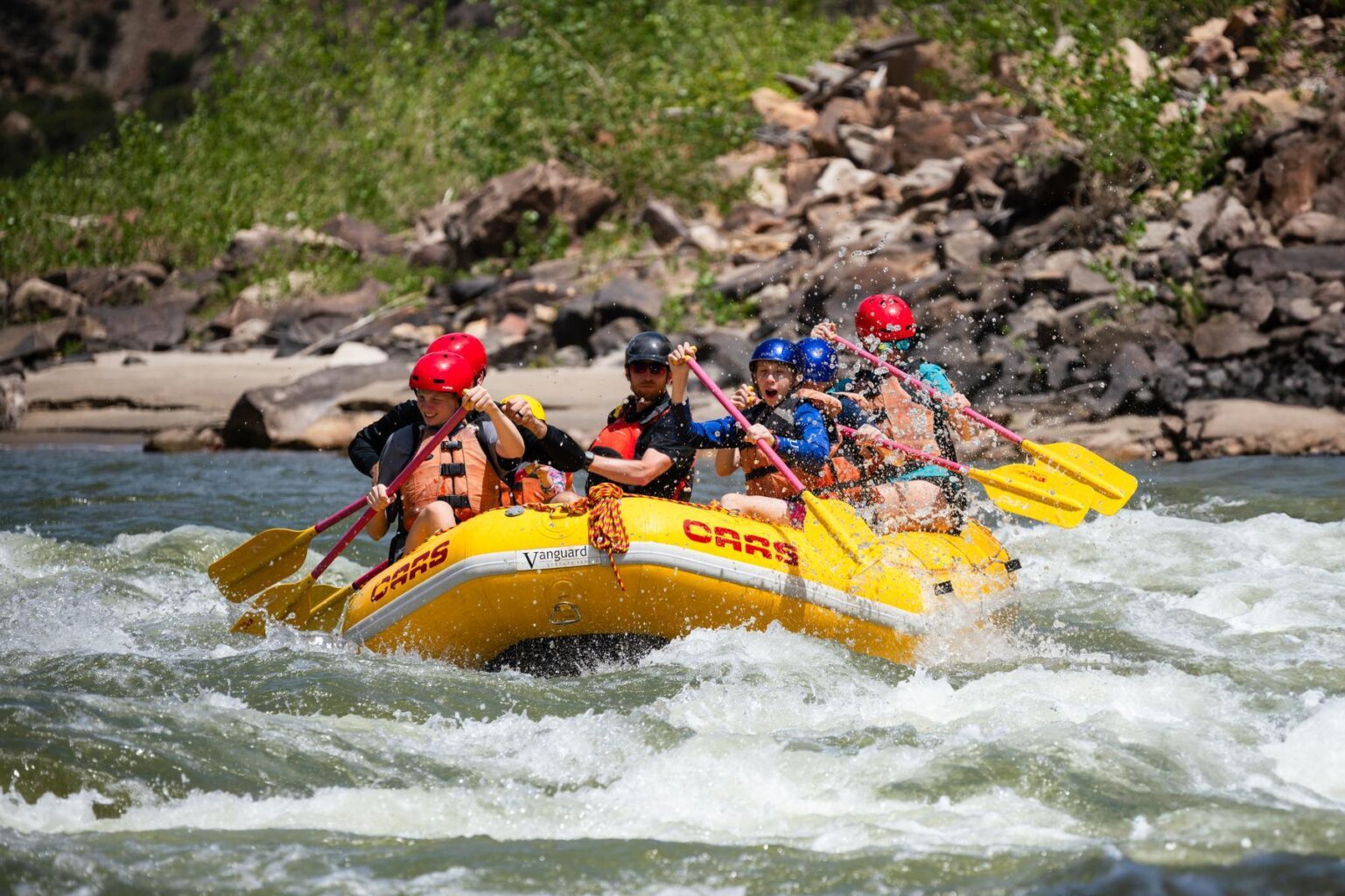 A family with older children splash through a rapid on the Green River through Split Mountain Canyon during a rafting trip with OARS in 2025.