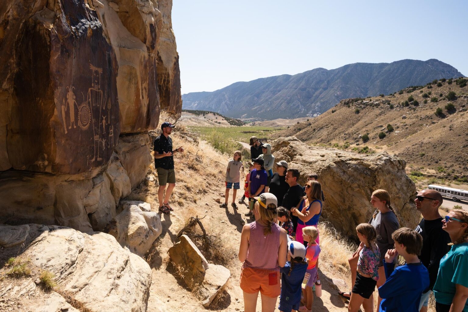 A group of guests on an OARS rafting trip observe petroglyphs during a trip in Split Mountain Canyon in 2025.
