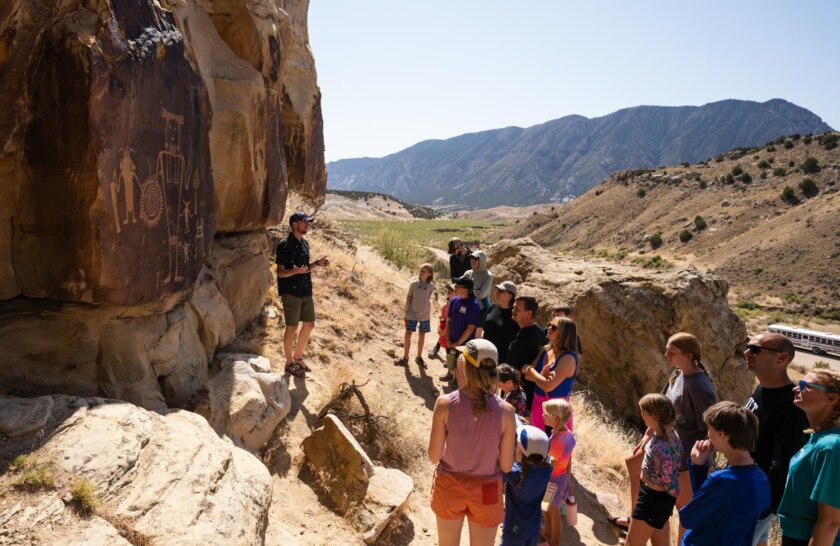 A group of guests on an OARS rafting trip observe petroglyphs during a trip in Split Mountain Canyon in 2025.