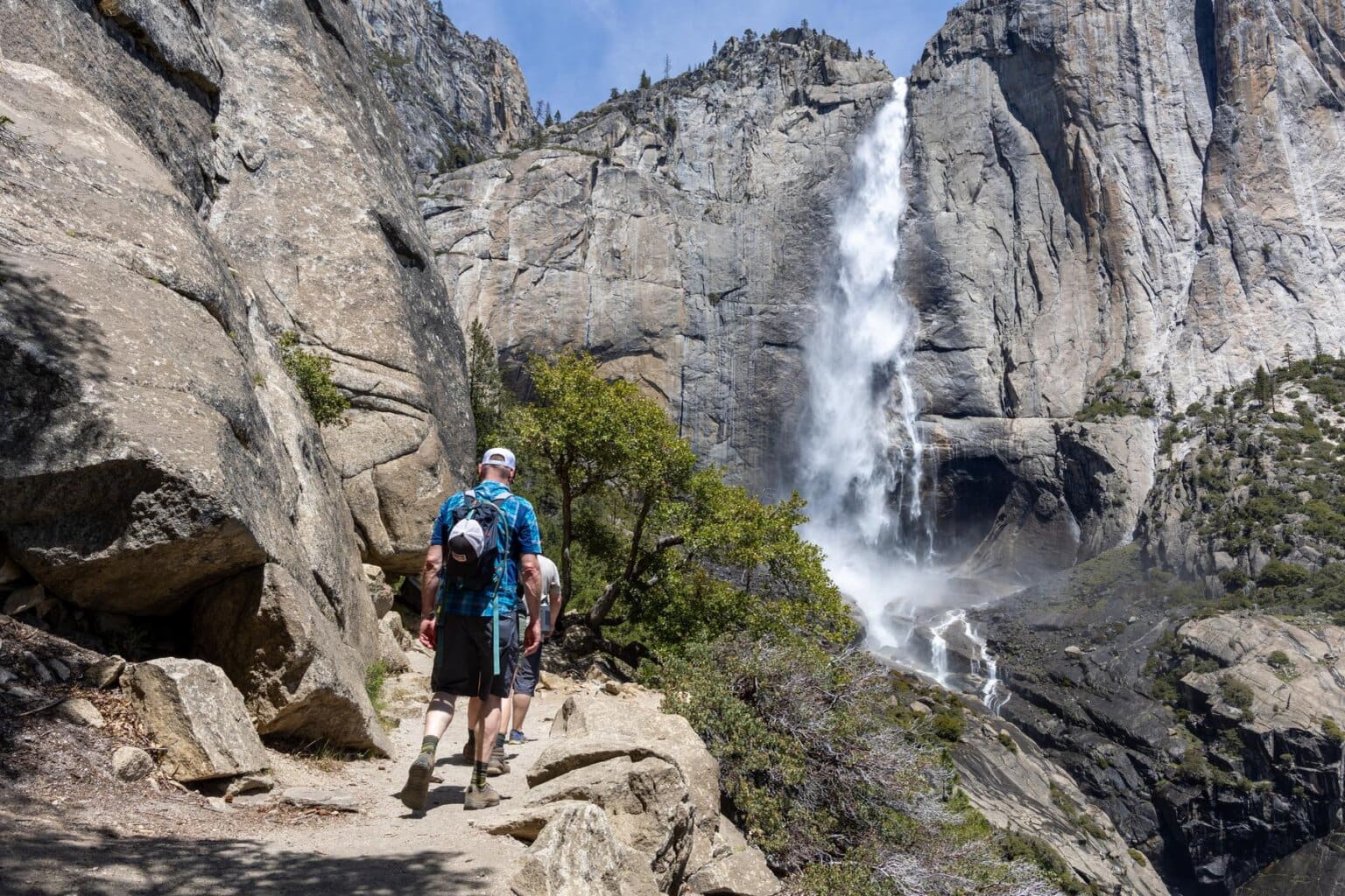Hikers make their way past Upper Yosemite Falls in Yosemite National Park