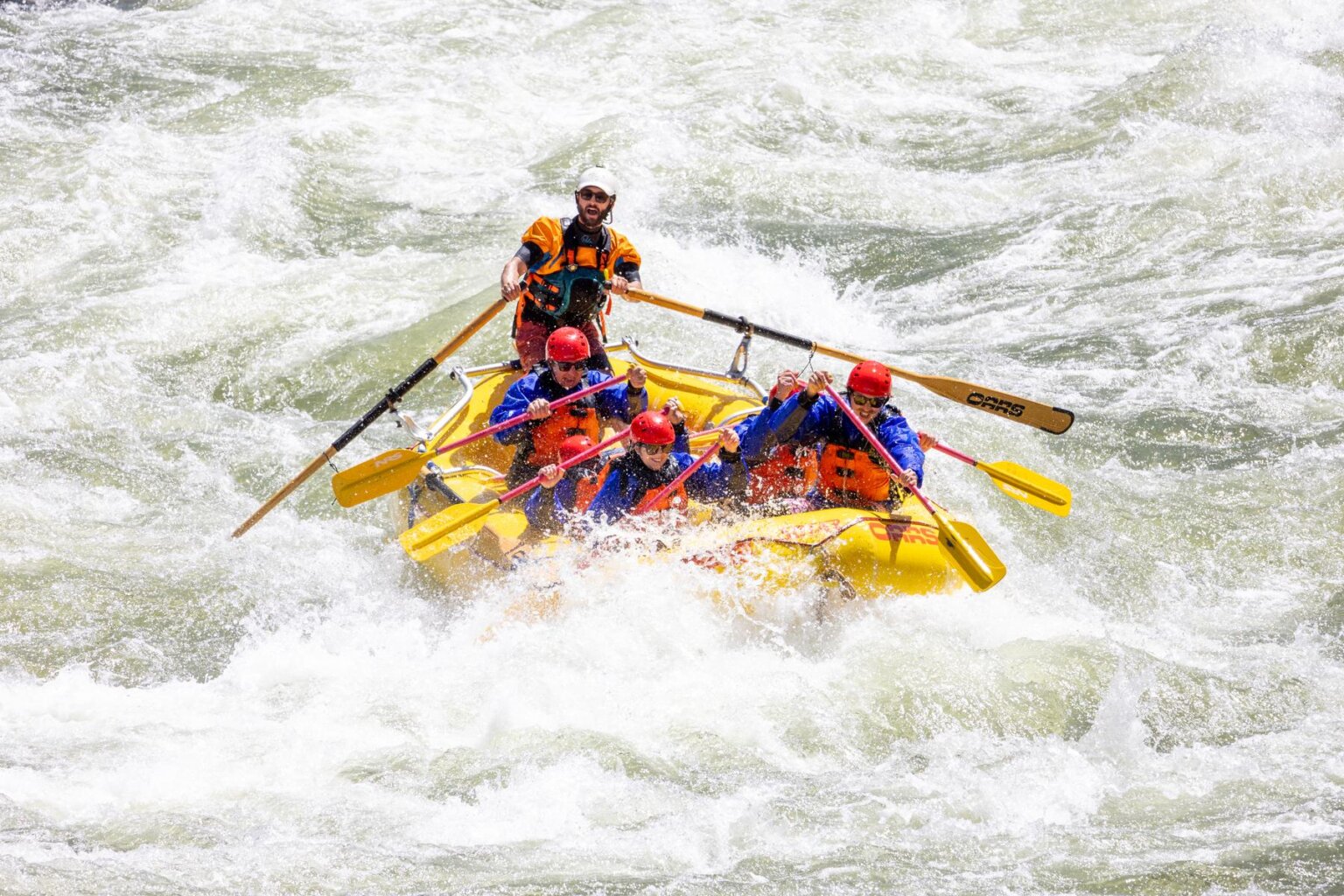 A yellow raft and its passengers engulfed by whitewater on California's Merced River