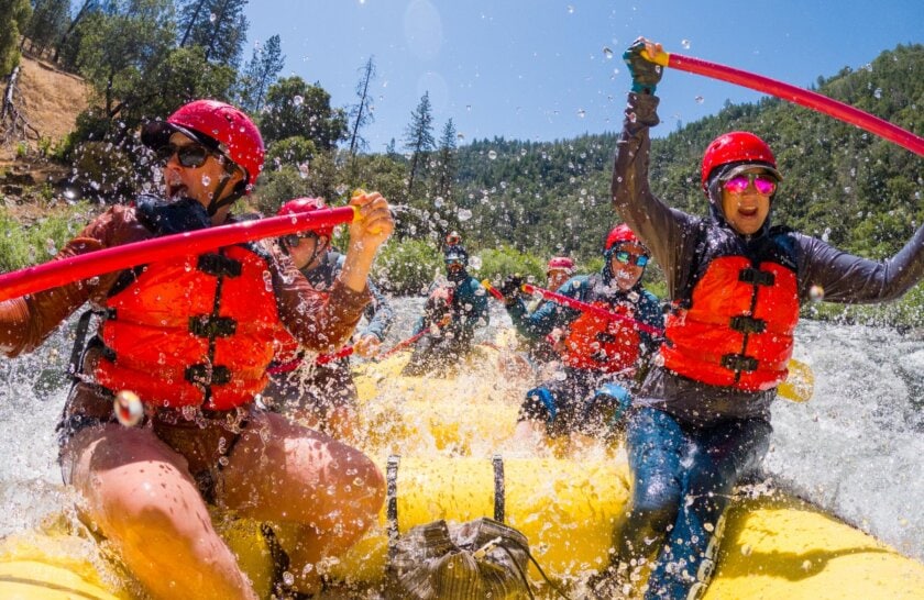 A raft full of people being splashed by whitewater