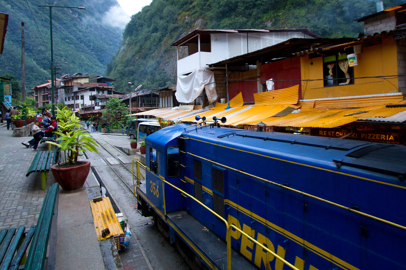 A train in Peru rolls through a misty mountain town.