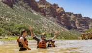 Three adult guests in personal flotation devices have a swim in the Green River through Split Mountain.