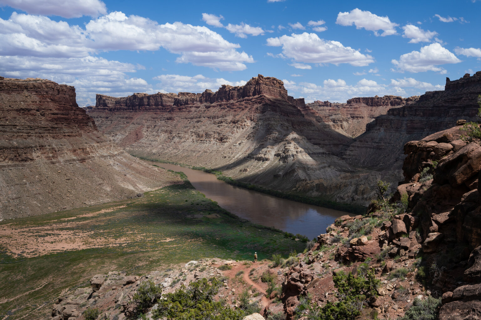 A wide shot of Stillwater Canyon with a tiny hiker above the river.