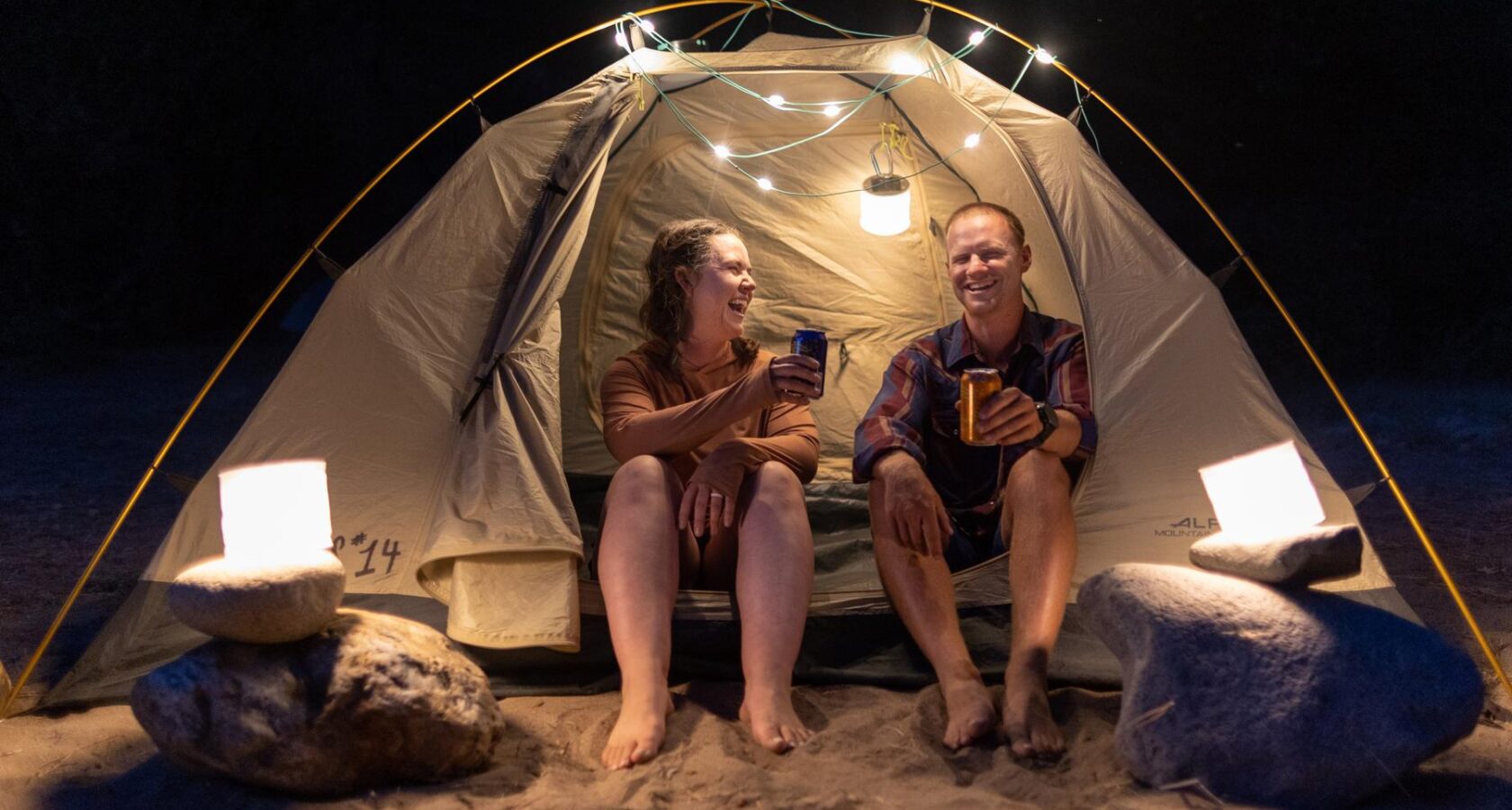 Friends toast at a tent illuminated by solar lights.