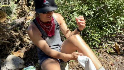 A hiker uses a body wipe to clean the dirt off of her legs after a big hike