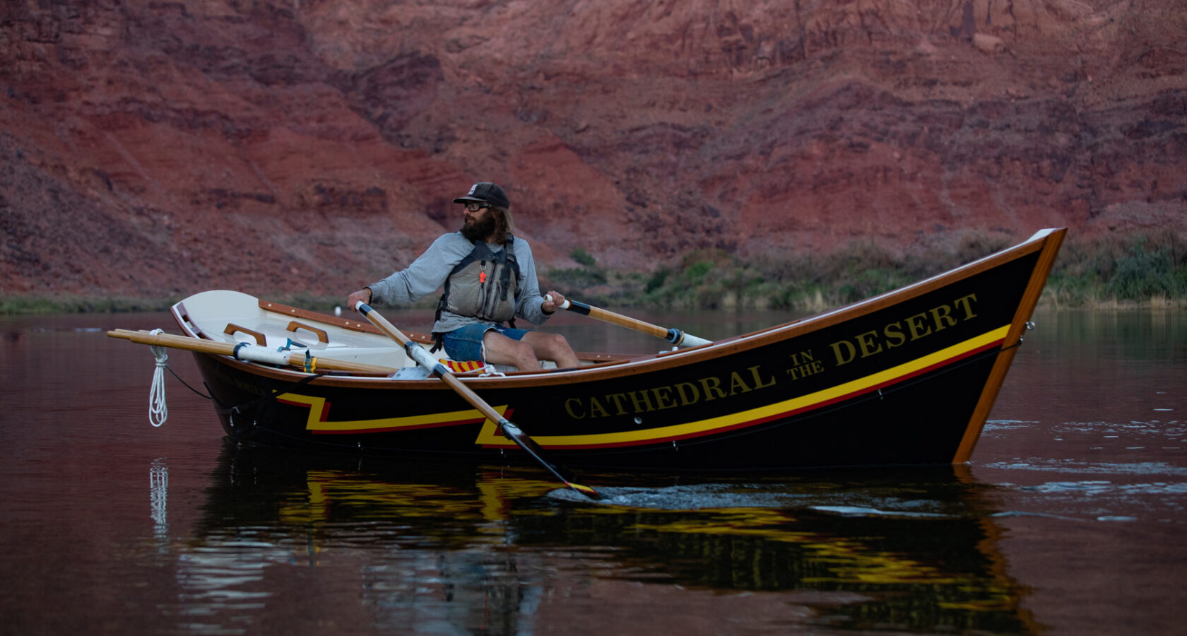 A river guides rows a wooden dory named Cathedral in the Desert