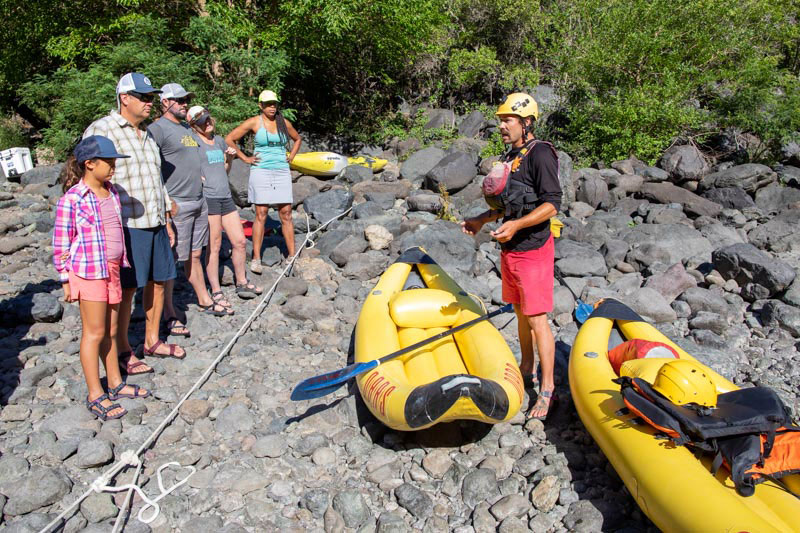 An OARS guide talks to a group of guests about inflatable kayaking.