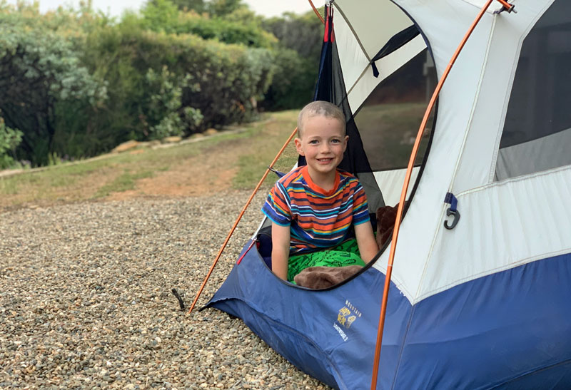 child smiling in tent while camping