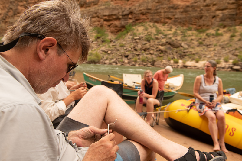 A man making clay beads on a Grand Canyon rafting trip