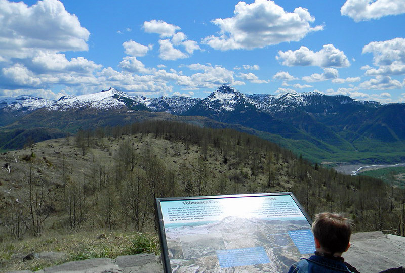 A boy looks at a placard overlooking Mt. St. Helends, a family vacation idea for a Pacific Northwest adventure