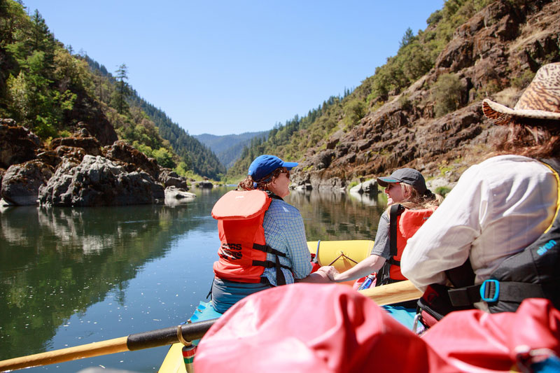 Women on a raft in long-sleeves and hats for sun protection