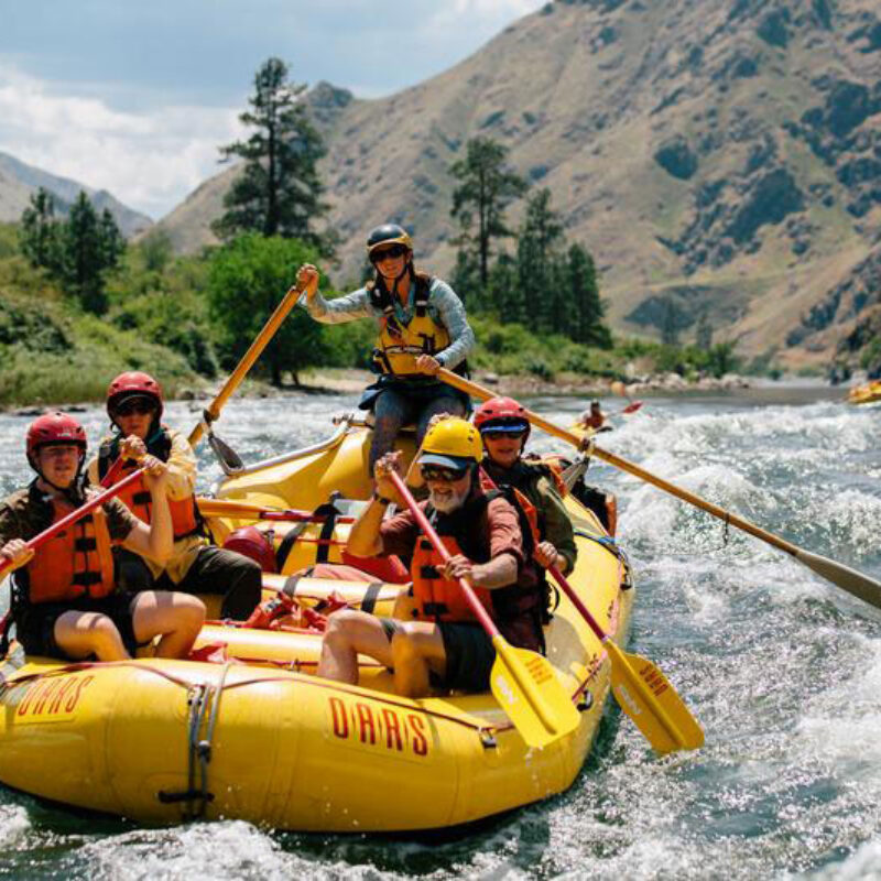 A group of people paddle through a rapid in a yellow raft on an OARS Snake River through Hells Canyon trip in Idaho.